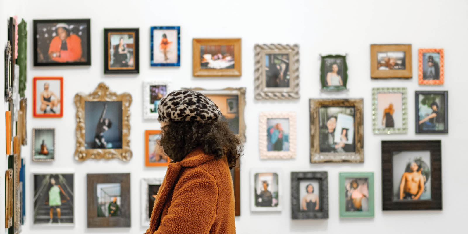 Woman standing in El Museo surrounded by a wall of pictures