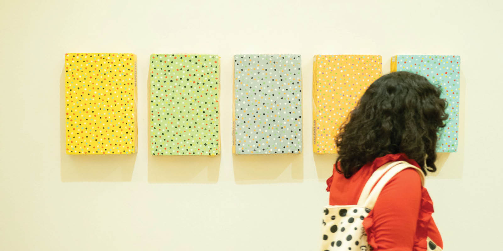 Woman passing by an array of paintings at El Museo