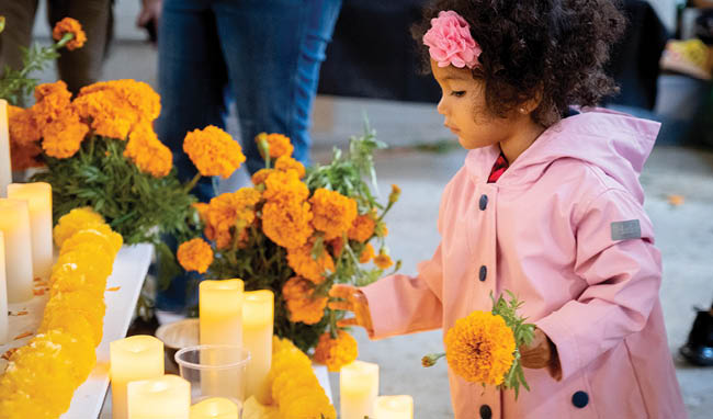 a young girl wearing a pink coat and holding flowers