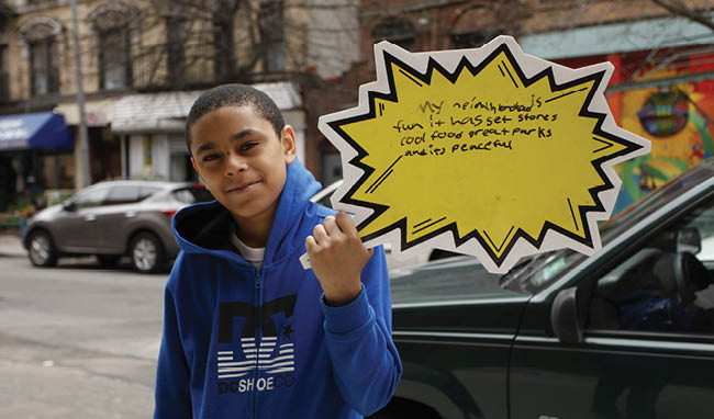 A young boy holding a yellow and white sign