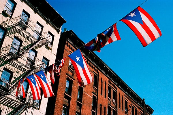 A row of flags of Puerto Rico hung from strings that run along a street.